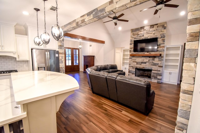 living room featuring french doors, dark hardwood / wood-style flooring, ceiling fan with notable chandelier, a stone fireplace, and lofted ceiling