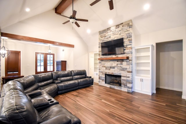 living room featuring french doors, beamed ceiling, hardwood / wood-style floors, a fireplace, and ceiling fan with notable chandelier