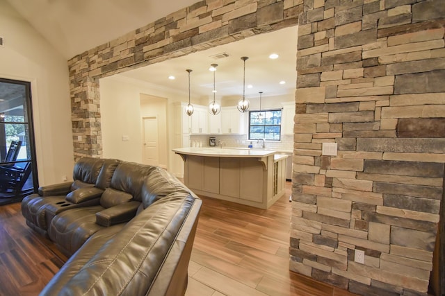 living room with light hardwood / wood-style floors, crown molding, lofted ceiling, and sink