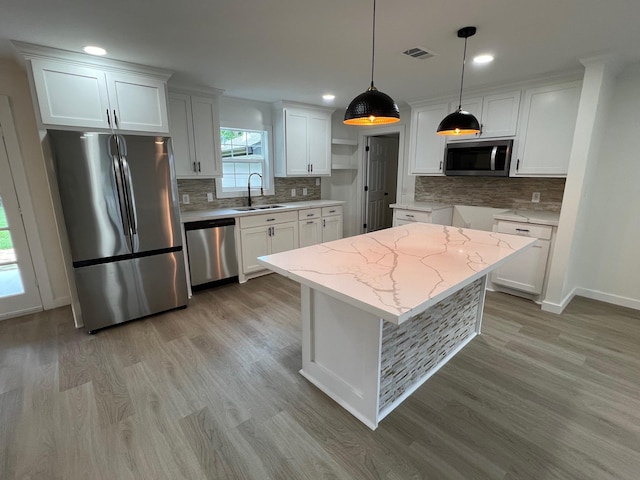 kitchen featuring white cabinets, stainless steel appliances, hanging light fixtures, and sink