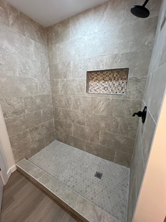 bathroom featuring wood-type flooring and tiled shower