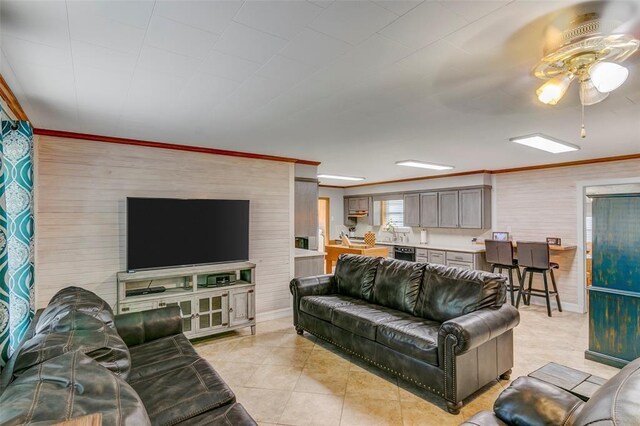 living room featuring ceiling fan, light tile patterned floors, and crown molding