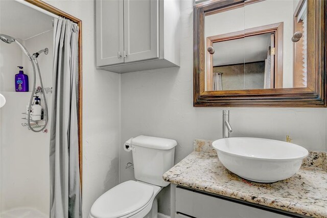 bathroom with toilet, vanity, and walk in shower