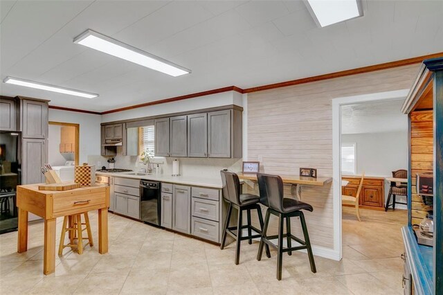 kitchen with sink, gas cooktop, black dishwasher, crown molding, and a kitchen bar