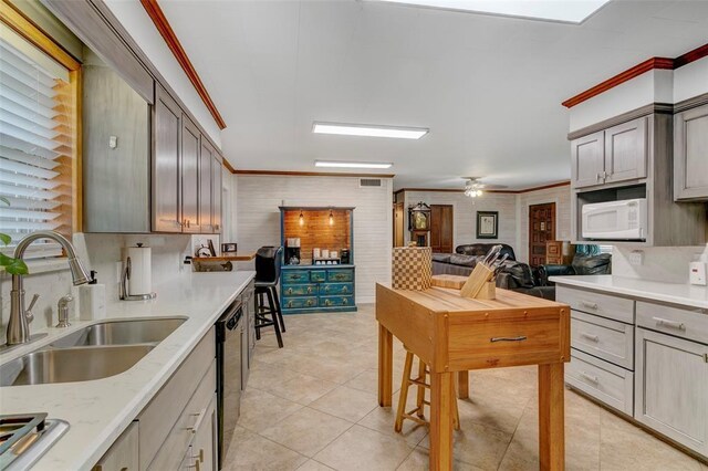 kitchen featuring dishwasher, light tile patterned floors, crown molding, and sink