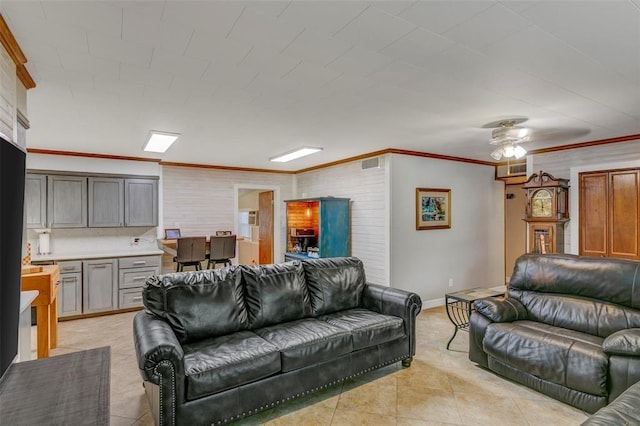 living room with light tile patterned floors, ceiling fan, and crown molding