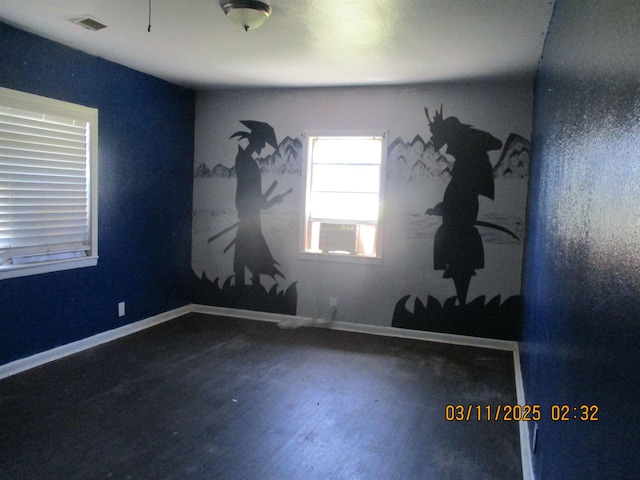 spare room featuring visible vents, baseboards, and wood finished floors