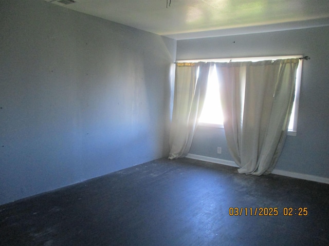 unfurnished room featuring concrete floors and baseboards