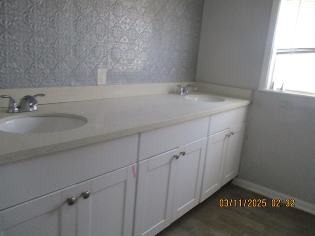 bathroom featuring double vanity, wood finished floors, and a sink