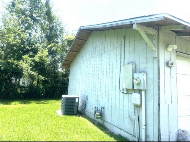 view of side of property featuring central AC unit and a lawn