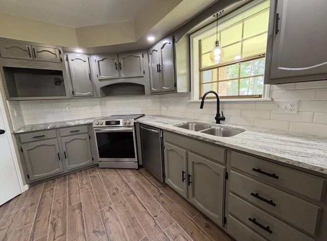 1401 Buckingham Dr, Orange, TX 77632 - kitchen featuring appliances with stainless steel finishes, a sink, wood finished floors, gray cabinets, and backsplash