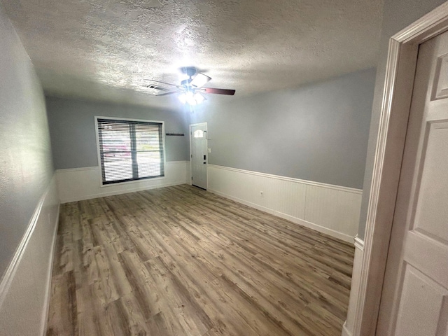 850 Orange St, Vidor, TX 77662 - empty room featuring wood finished floors, a textured ceiling, wainscoting, and a ceiling fan