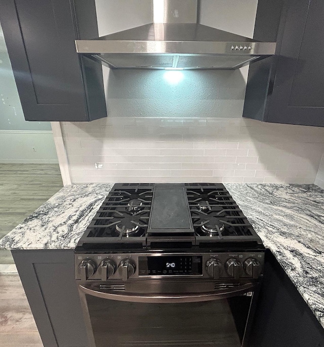 850 Orange St, Vidor, TX 77662 - kitchen view of stainless steel gas range oven, exhaust hood, wood finished floors, backsplash, and light stone countertops