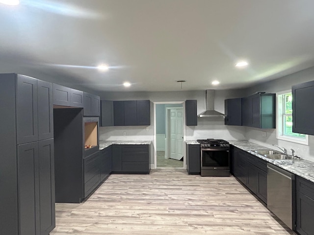 850 Orange St, Vidor, TX 77662 - kitchen featuring appliances with stainless steel finishes, wall chimney exhaust hood, recessed lighting, light wood-type flooring, and light stone counters