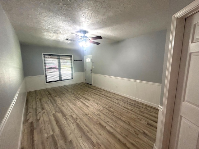 850 Orange St, Vidor, TX 77662 - unfurnished room featuring wood finished floors, a textured ceiling, a ceiling fan, and wainscoting