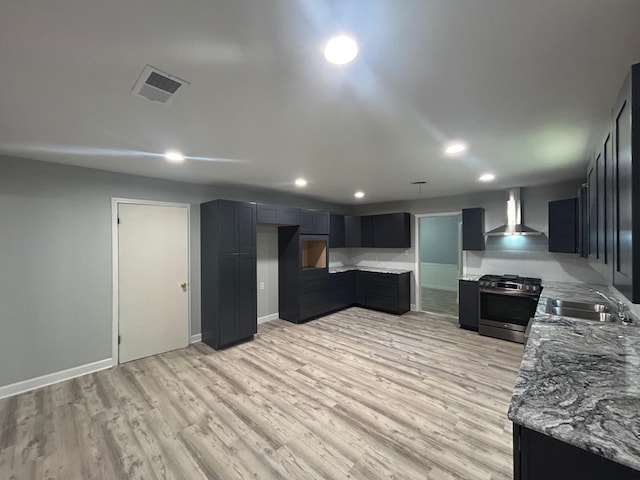 850 Orange St, Vidor, TX 77662 - kitchen featuring stainless steel range with gas cooktop, wall chimney exhaust hood, recessed lighting, light wood finished floors, and light stone countertops
