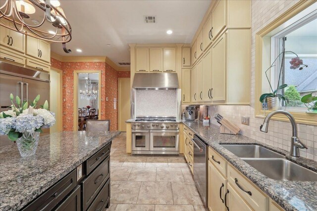 5160 Littlechase Dr, Beaumont, TX 77706 - kitchen featuring under cabinet range hood, appliances with stainless steel finishes, cream cabinets, a chandelier, and a sink