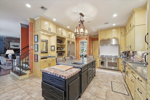 5160 Littlechase Dr, Beaumont, TX 77706 - kitchen with a sink, cream cabinets, under cabinet range hood, stainless steel appliances, and recessed lighting