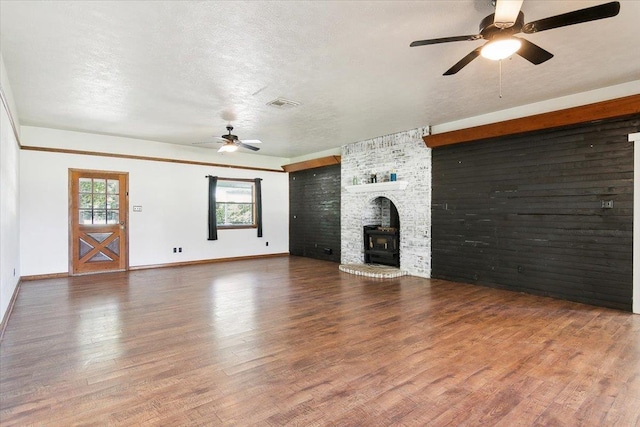 unfurnished living room with a wood stove, ceiling fan, a textured ceiling, and hardwood / wood-style flooring