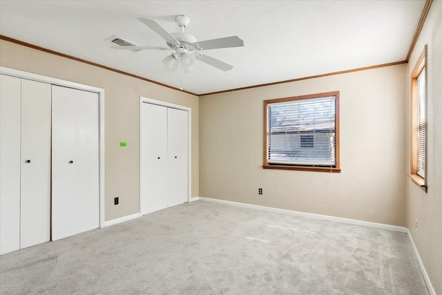 unfurnished bedroom with multiple windows, ceiling fan, and multiple closets