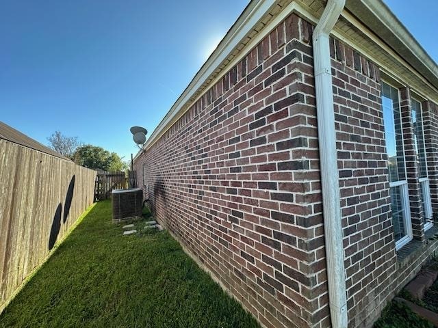 view of side of home featuring a yard and central air condition unit