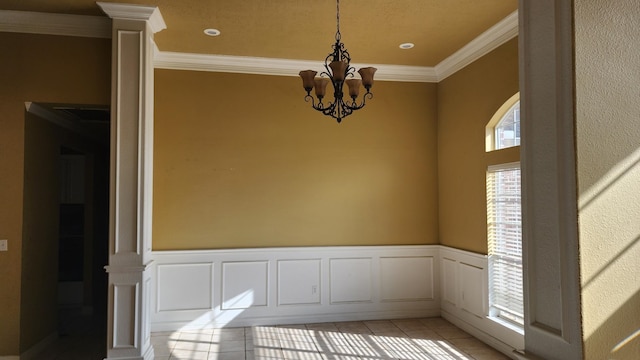 unfurnished dining area featuring light tile patterned floors, crown molding, a chandelier, and ornate columns