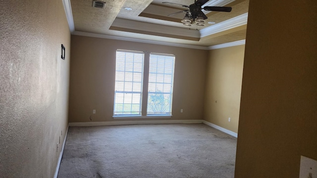 empty room featuring ceiling fan, ornamental molding, a tray ceiling, and carpet