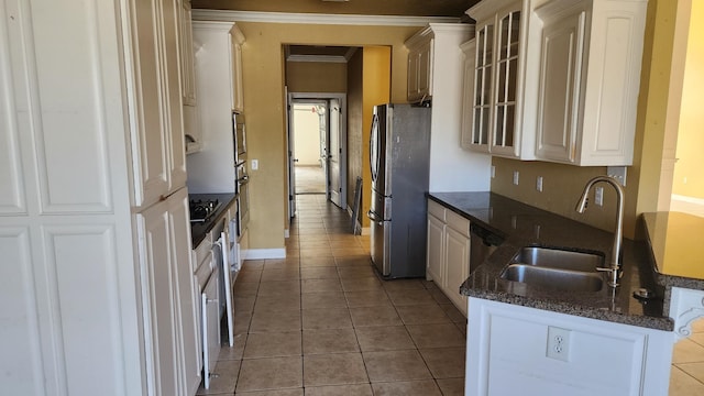 kitchen featuring sink, light tile patterned floors, white cabinetry, stainless steel appliances, and dark stone counters