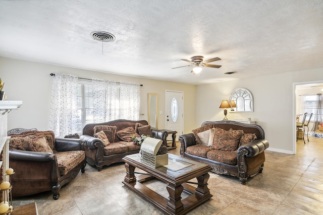 living room featuring ceiling fan and a textured ceiling