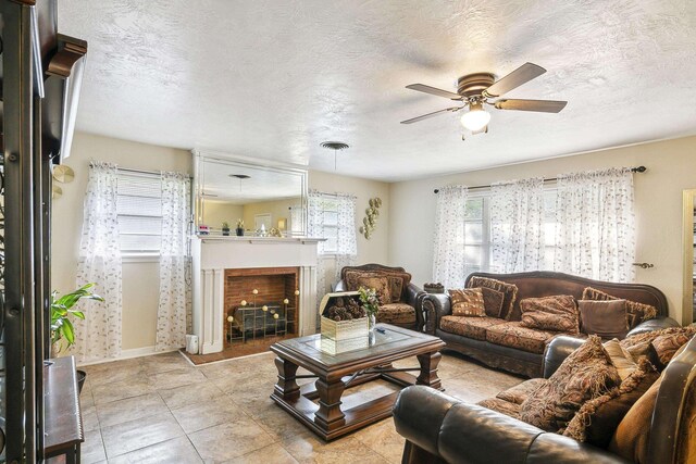 tiled living room with ceiling fan and a textured ceiling