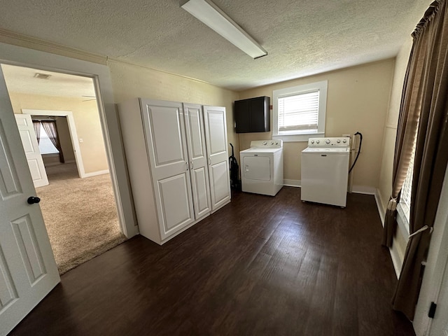 laundry area with washing machine and clothes dryer, dark hardwood / wood-style floors, cabinets, and a textured ceiling