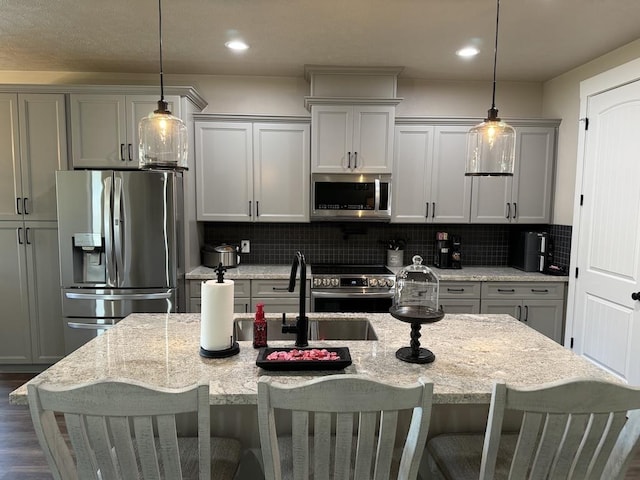 kitchen featuring a breakfast bar area, backsplash, light stone counters, and stainless steel appliances