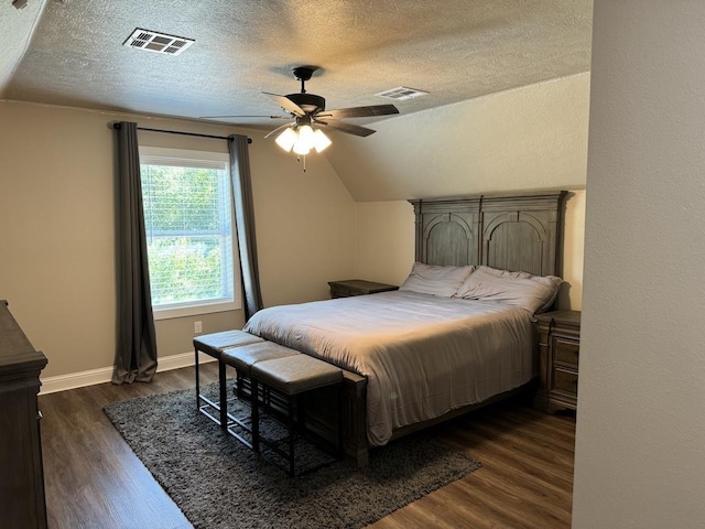 bedroom with a textured ceiling, vaulted ceiling, ceiling fan, and dark wood-type flooring