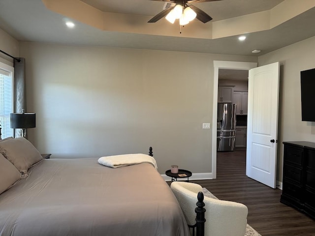 bedroom with ceiling fan, stainless steel fridge, a raised ceiling, and dark hardwood / wood-style flooring