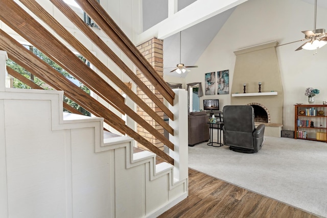 1135 Brandywine St, Beaumont, TX 77706 - stairway featuring high vaulted ceiling, a ceiling fan, a large fireplace, and wood finished floors