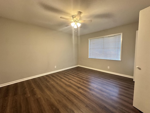 empty room with a ceiling fan, dark wood finished floors, and baseboards