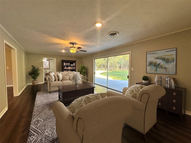 living area with visible vents, ornamental molding, a textured ceiling, wood finished floors, and baseboards