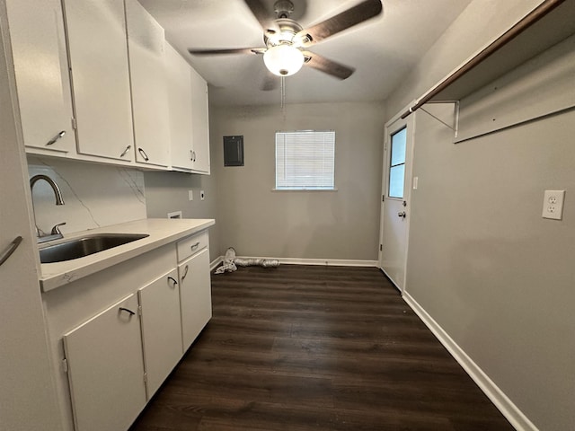 kitchen featuring dark wood-type flooring, a sink, baseboards, white cabinets, and light countertops