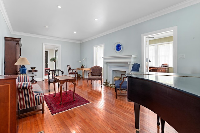 living room with light wood-type flooring, a premium fireplace, crown molding, and a wealth of natural light