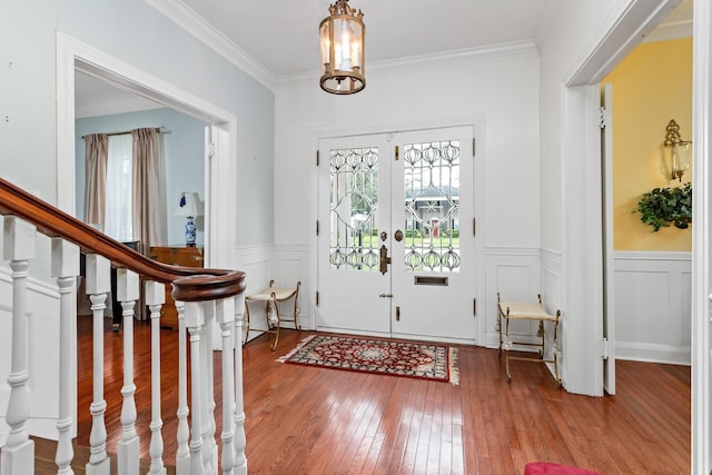 entryway with hardwood / wood-style floors, a chandelier, ornamental molding, and french doors