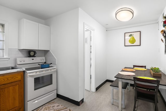 kitchen featuring tasteful backsplash, white cabinetry, and white electric range oven