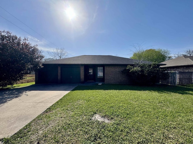 ranch-style home featuring brick siding, fence, concrete driveway, a front yard, and an attached garage