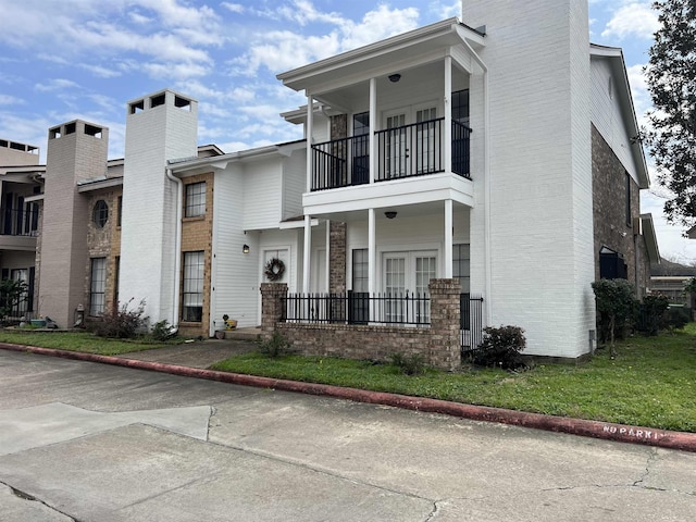 view of front of property featuring a front yard and a balcony