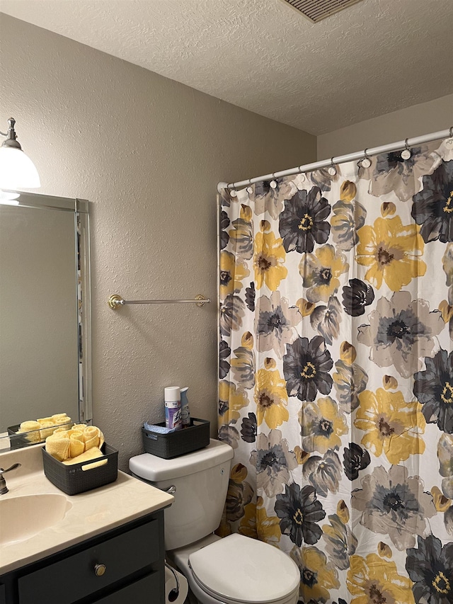 bathroom with vanity, toilet, and a textured ceiling