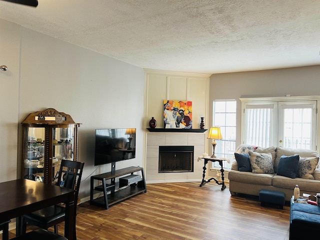 living room featuring hardwood / wood-style flooring, a textured ceiling, and a tile fireplace