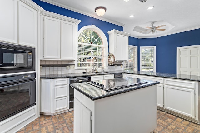 kitchen featuring sink, a kitchen island, tasteful backsplash, white cabinets, and black appliances