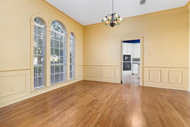 empty room with crown molding, light hardwood / wood-style flooring, and a notable chandelier