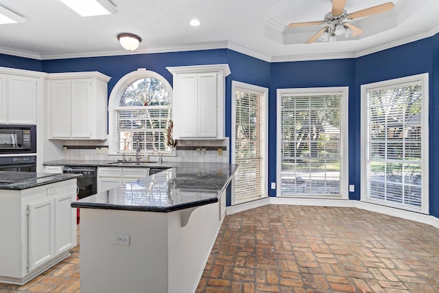 kitchen featuring decorative backsplash, sink, white cabinets, and black appliances