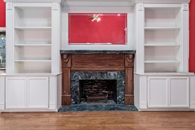 unfurnished living room featuring built in features, a high end fireplace, and wood-type flooring