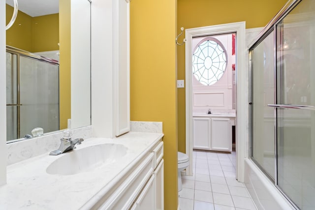 full bathroom featuring tile patterned flooring, vanity, toilet, and bath / shower combo with glass door